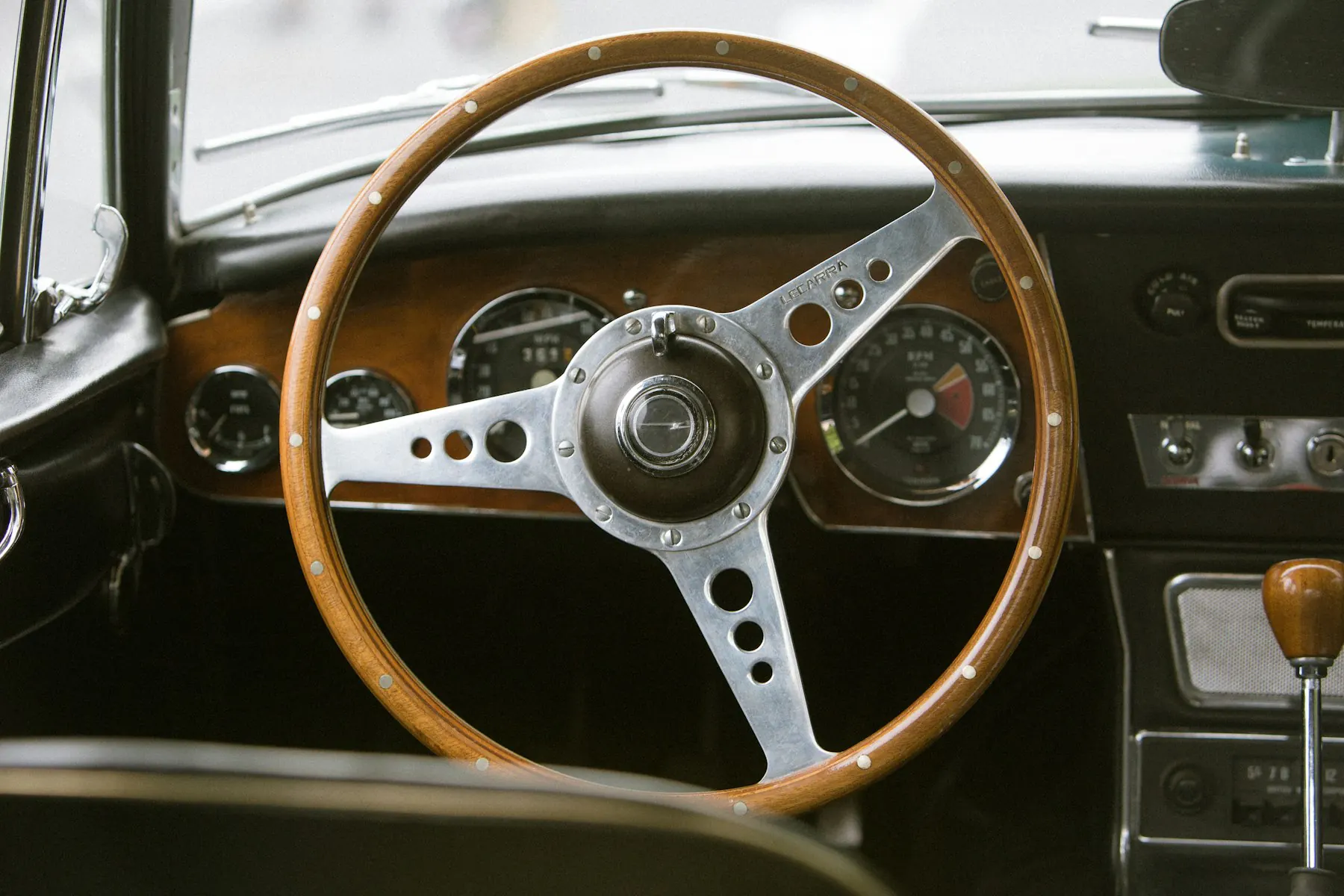 Wood-rimmed steering wheel and dashboard of a classic sports car
