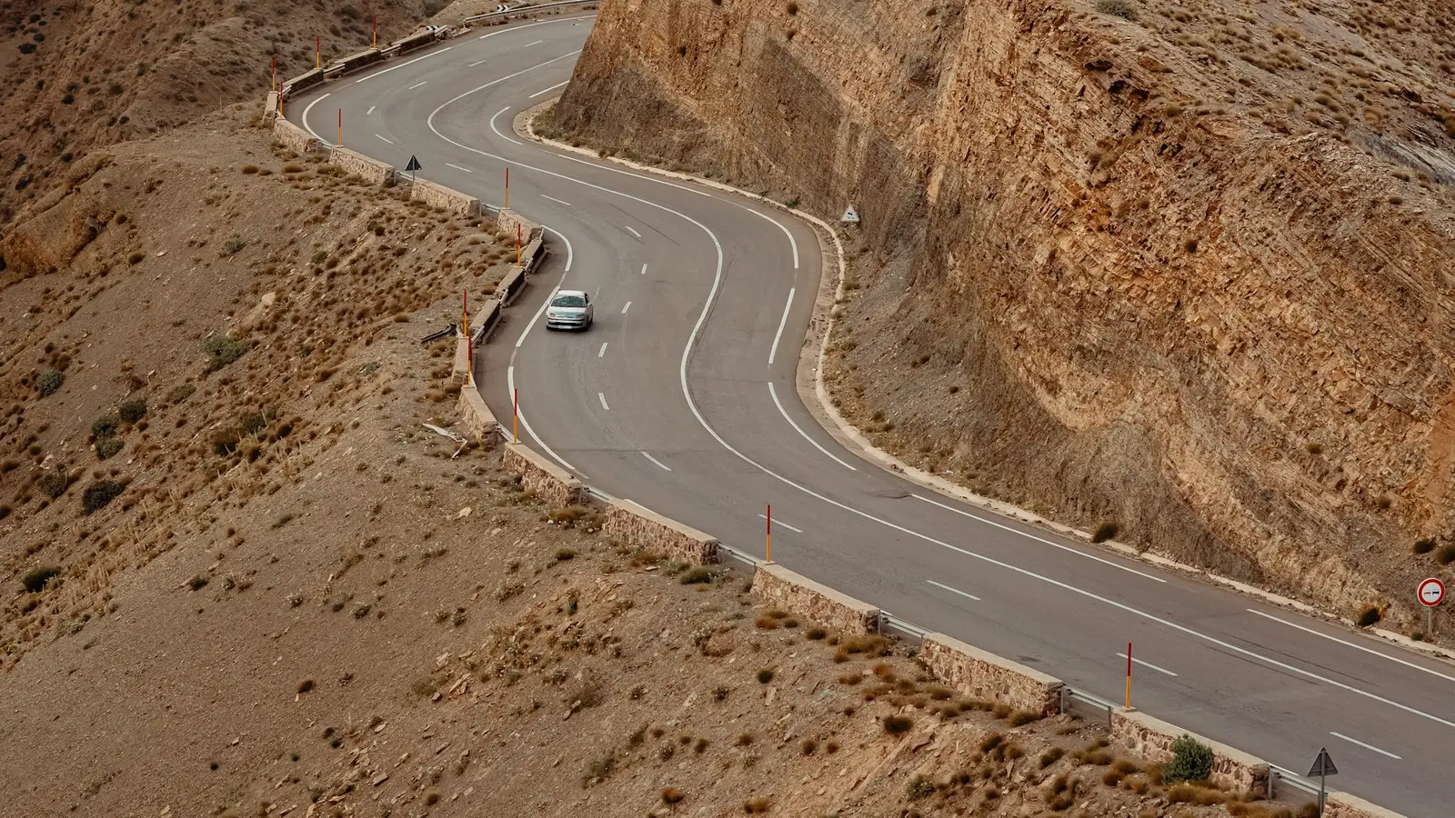 A lone car on a winding mountain road in the High Atlas, Morocco