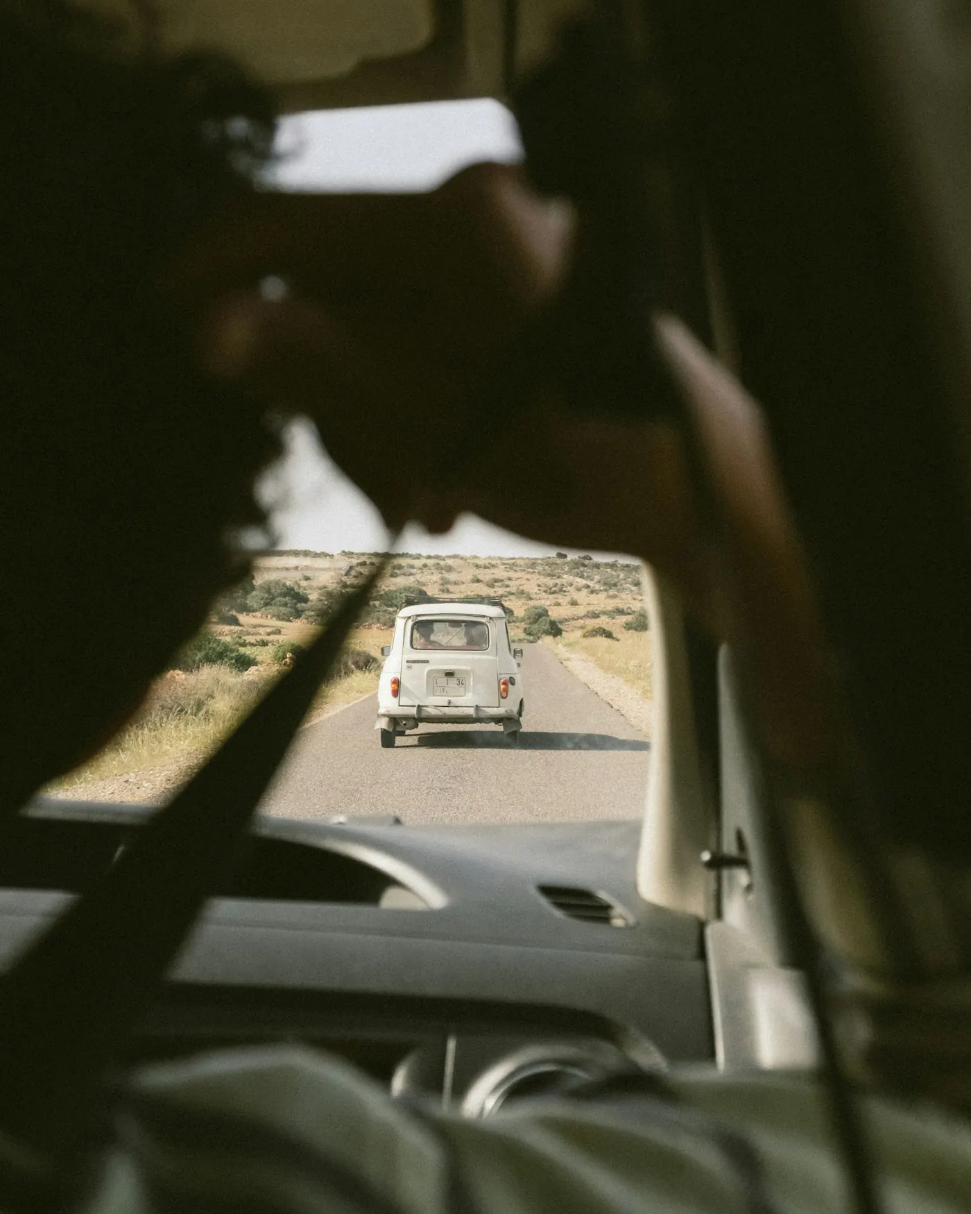 View through a windscreen of a classic car ahead on a desert road