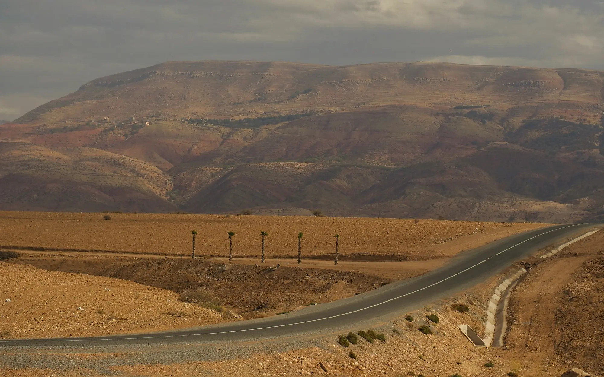 Empty asphalt road crossing a plain toward the mountains of Morocco